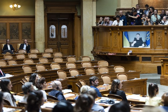 epa10692414 Presiden Ukraina Volodymyr Zelensky ditampilkan di layar di depan kursi kosong anggota partai sayap kanan SVP selama pidatonya di depan anggota Parlemen Swiss,...
