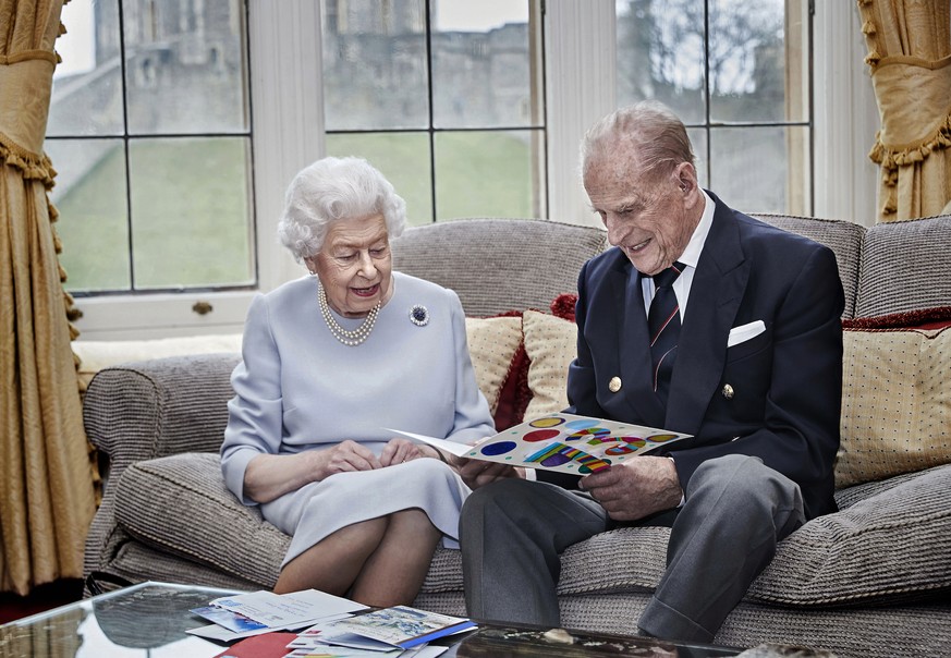 In this image released on Thursday Nov. 19, 2020, Britain's Queen Elizabeth II and Prince Philip, Duke of Edinburgh look at a homemade wedding anniversary card, given to them by their great grand ...