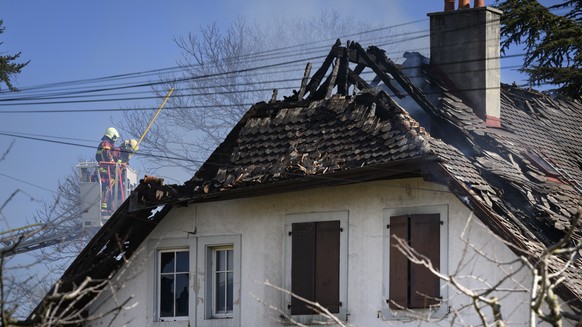 Firefighters watch from a ladder a villa where bodies were found after a fire, in Yverdon-les-bains, Switzerland, Thursday, March 9, 2023. An explosion followed by a fire took place Thursday morning i ...