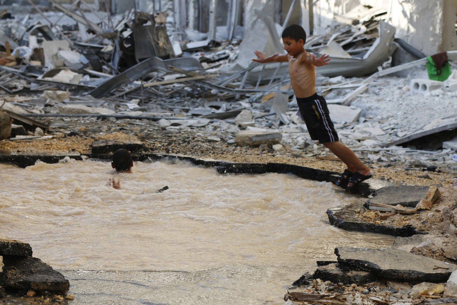 Ein Junge taucht in einen mit Wasser gefüllten Krater in Aleppo. Aktivisten sagten, der Krater sei durch eine Bombe von Assad-Truppen entstanden.&nbsp;