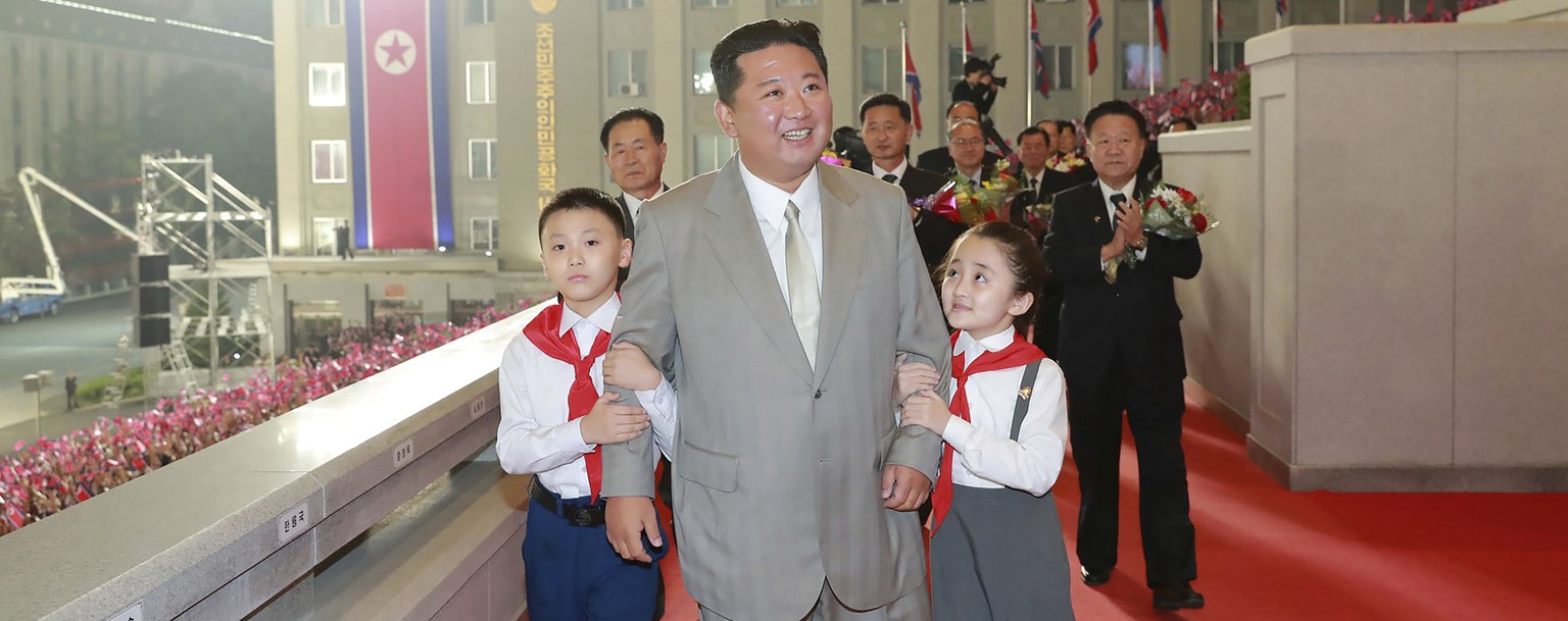 In this photo provided by the North Korean government, North Korean leader Kim Jong Un walks with children during a celebration of the nation