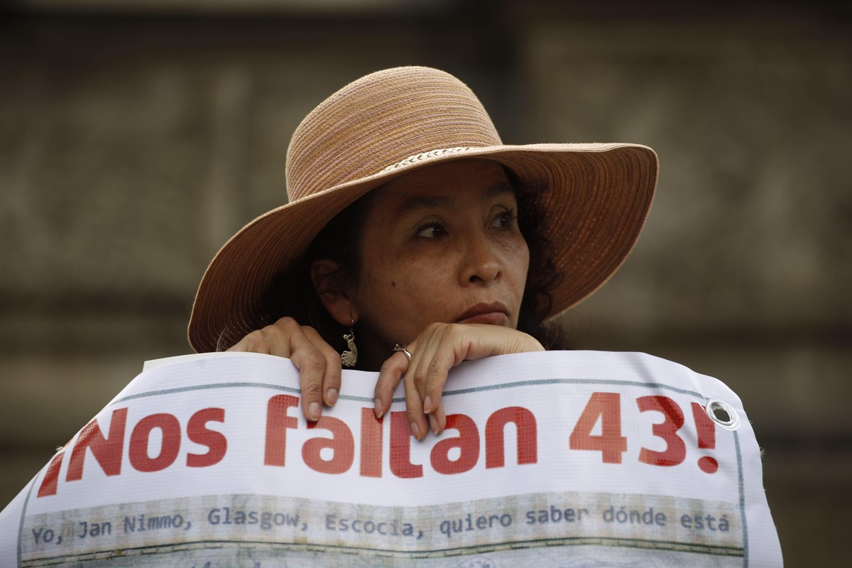 FILE - A woman carries a banner that reads in Spanish "We are missing 43," referring to the 43 missing students from a rural teachers college during a march in Mexico City, Thursday, Nov. 26 ...