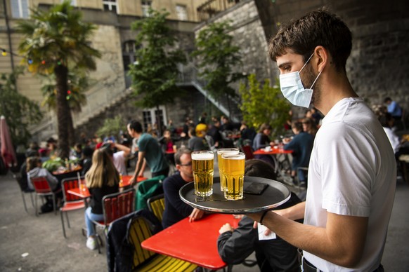 ARCHIVBILD ZUR GEPLANTEN WIEDEREROEFFNUNG VON RESTAURANTTERRASSEN AB DEM 23. MAERZ, AM FREITAG, 12. MAERZ 2021 - Un serveur avec un masque porte des bieres sur un plateau aux clients de la terrasse de ...