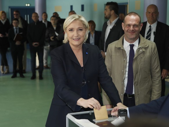 CORRECTS NAME OF THE MAN - Far-right leader and candidate for the 2017 French presidential election Marine Le Pen casts her vote for the first-round presidential election, while National Front Henin-B ...