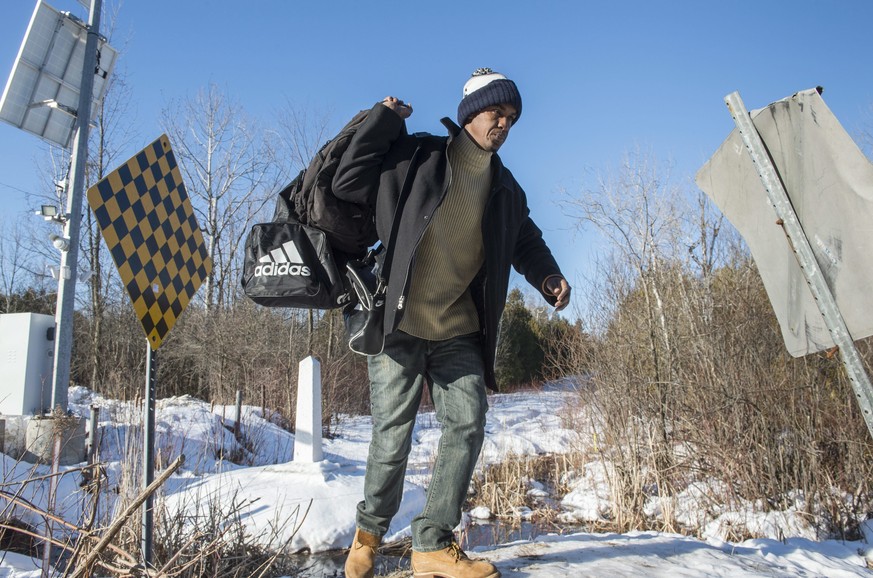 A refugee claimant from Mauritania crosses the border into Canada from the United States, Monday, Feb. 20, 2017 near Hemmingford, Quebec. A growing number of people have been walking across the border ...