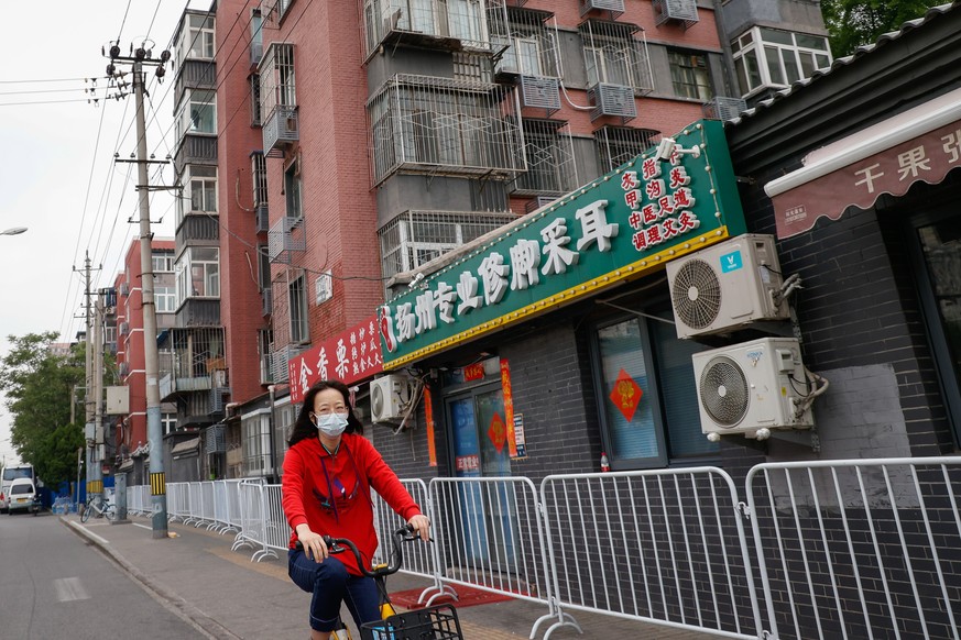 epa09915835 A woman bikes along an area under lockdown in Chaoyang district, Beijing, China, 29 April 2022. Beijing continues its tough restrictions with mass testing and recently closing down more es ...