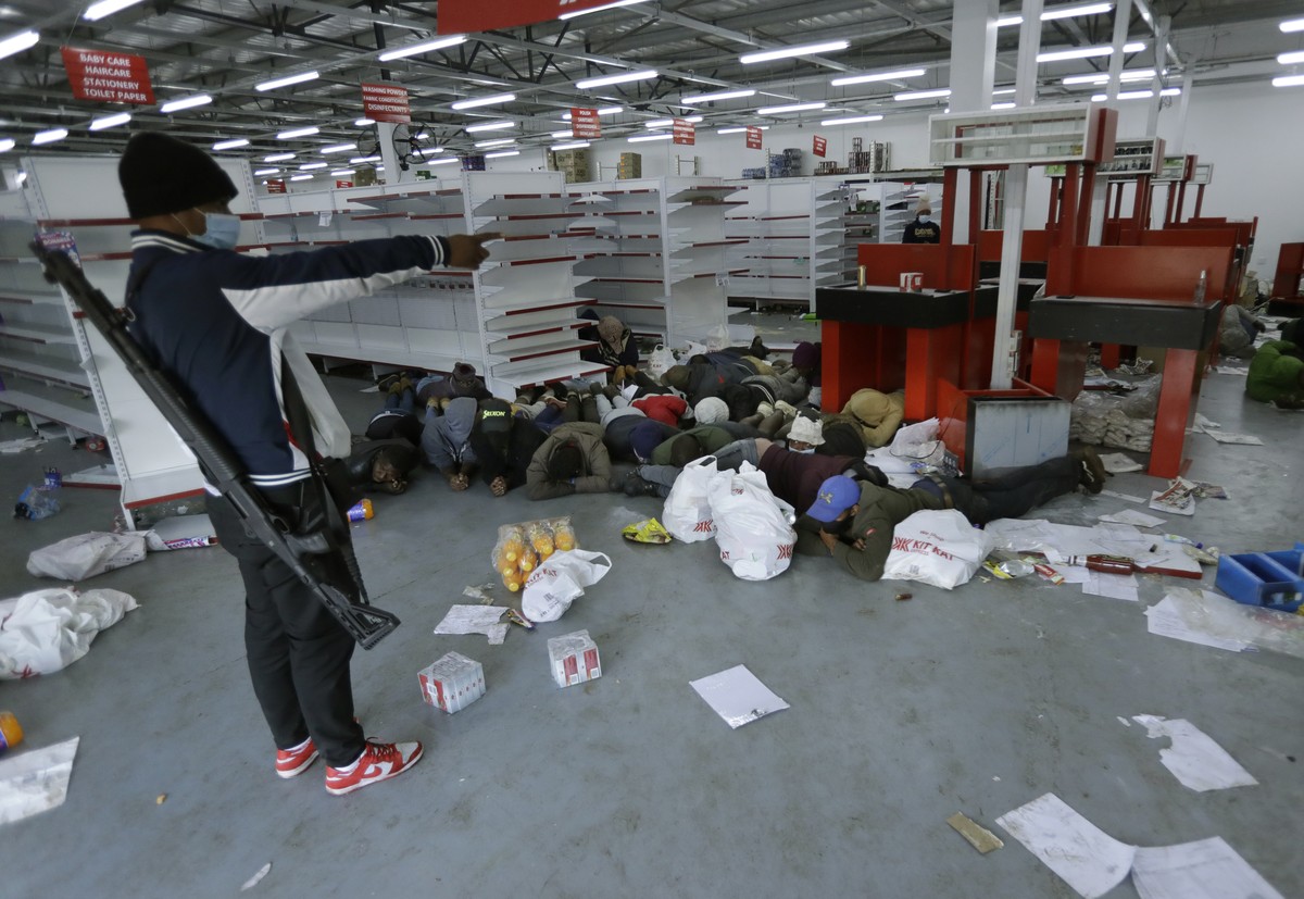 A security person aprehends looters inside a store in Vosloorus near Johannesburg, Tuesday July 13, 2021. South Africa's rioting continued Tuesday with the death toll rising to 32 as police and t ...