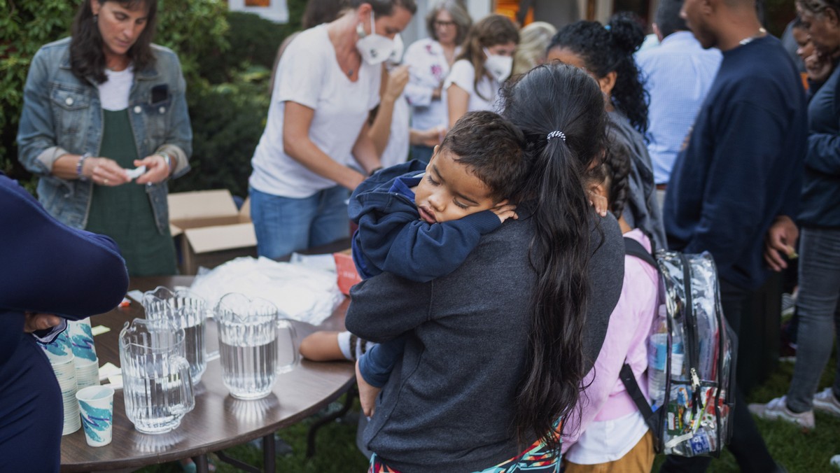 A woman, who is part of a group of immigrants that had just arrived, holds a child as they are fed outside St. Andrews Episcopal Church, Wednesday Sept. 14, 2022, in Edgartown, Mass., on Martha's ...