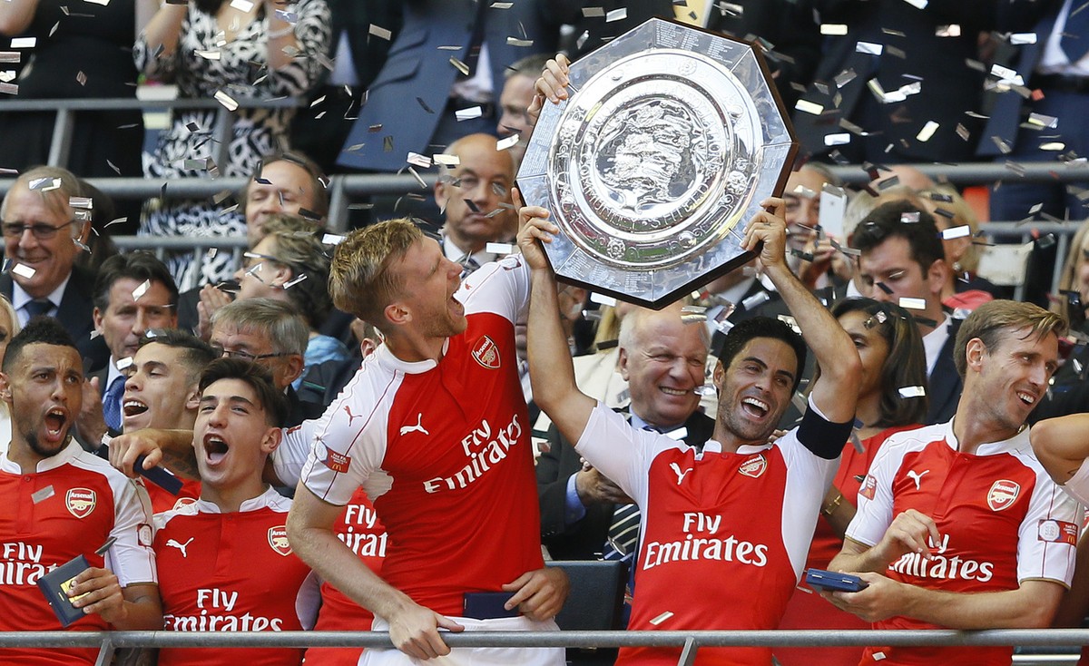 Arsenal's captain Per Mertesacker, centre, holds the trophy with Mikel Arteta, second right, after winning the English Community Shield soccer match between Arsenal and Chelsea at Wembley Stadium ...