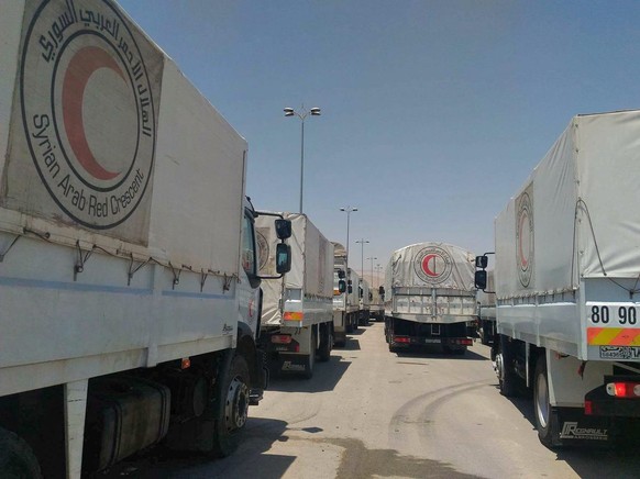 epa05397760 A handout picture made available by the Syrian Arab Red Crescent shows UN and Syrian Arab Red Crescent and Red Cross trucks delivering 37 loaded aid trucks to Zamalka and Erbeen towns in E ...