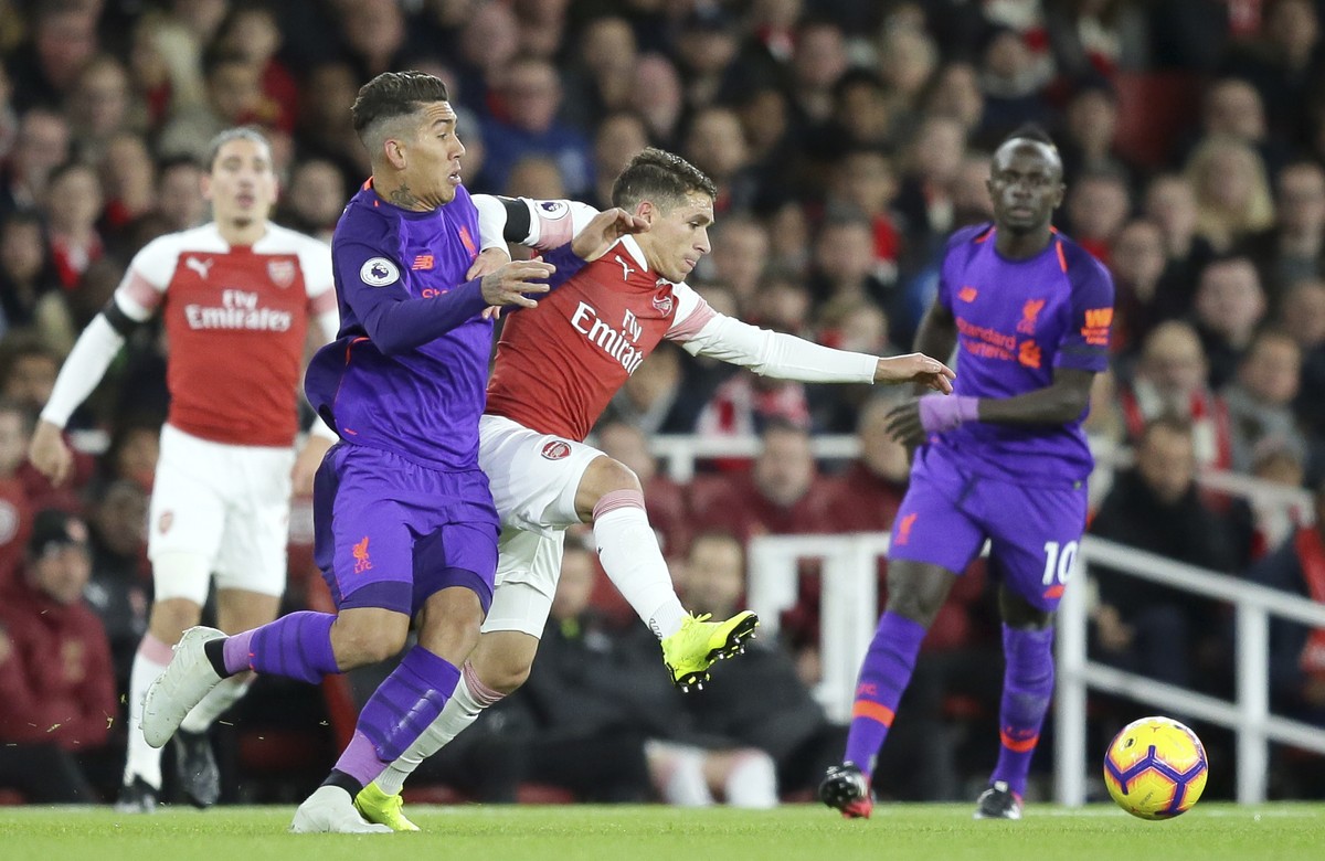 Liverpool's Roberto Firmino fights for the ball with Arsenal's Lucas Torreira, center, during the English Premier League soccer match between Arsenal and Liverpool at Emirates stadium in Lon ...