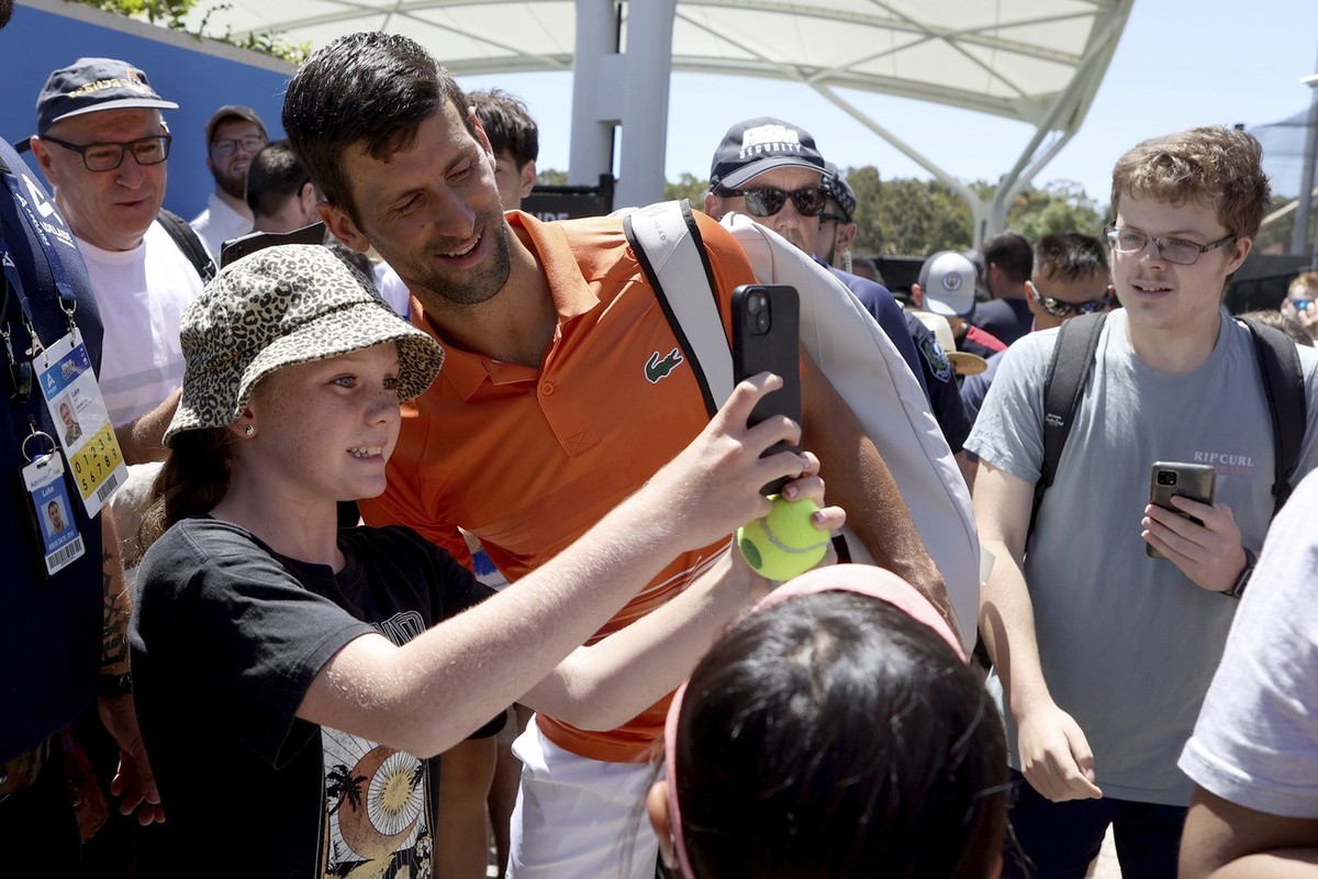 Serbia's Novak Djokovic, center, interacts with fans after his doubles match at the Adelaide International Tennis tournament in Adelaide, Australia, Monday, Jan. 2, 2023. (AP Photo/Kelly Barnes)