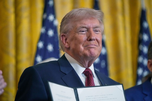 President Donald Trump holds up an executive order he just signed during an event on coal power in the East Room at the White House, Wednesday, Feb. 11, 2026, in Washington. (AP Photo/Mark Schiefelbei ...