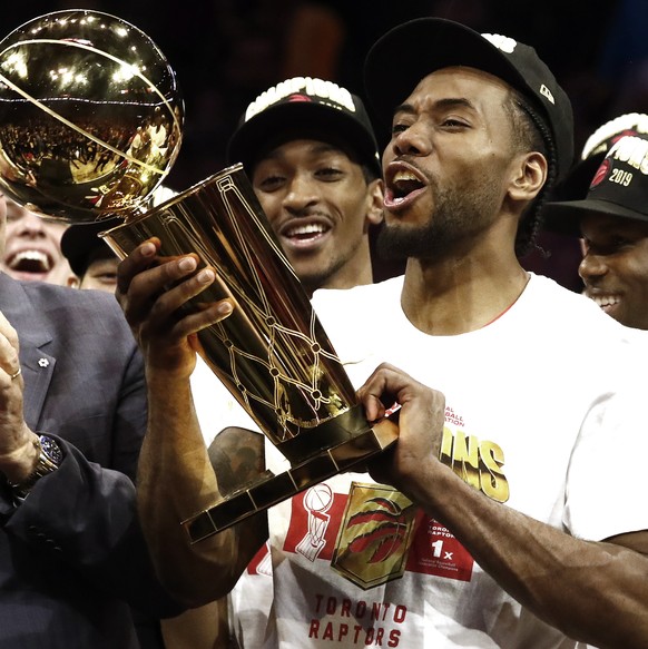 epa07647064 Toronto Raptors forward Kawhi Leonard (R) holds up the Larry O'Brien NBA Championship Trophy after beating the Golden State Warriors in the NBA Finals game six at Oracle Arena, in Oak ...