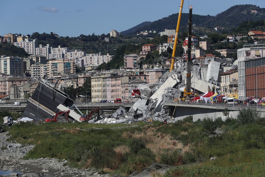 Rescuers work among the rubble of the Morandi highway bridge that collapsed in Genoa, northern Italy, Wednesday, Aug. 15, 2018. A large section of the bridge collapsed over an industrial area in the I ...