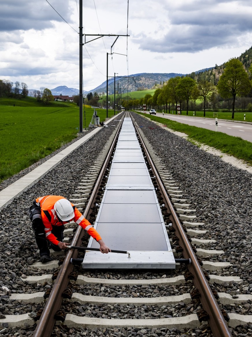 KEYPIX - Un ouvrier installe la premiere centrale solaire amovible sur voie ferree ouverte au trafic de l'entreprise Sun Ways le mardi 22 avril 2025 a Buttes dans la commune de Val-de-Travers. (K ...