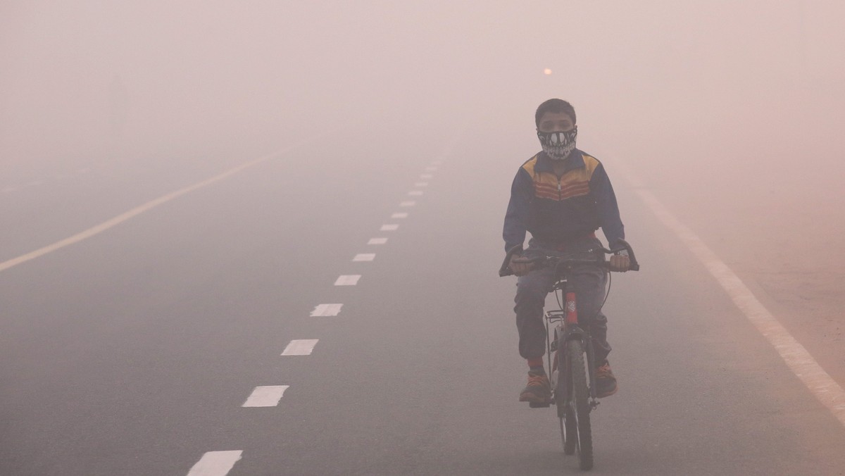 epa05610814 An Indian child wearing a face mask cycles in smog, one day after the Diwali festival, in New Delhi, India, 31 October 2016. According to a news report, hundreds of people faced breathing  ...