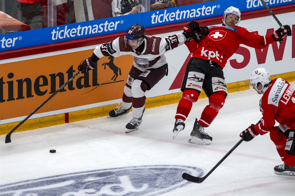 Latvia's Oskars Lapinskis, left, in action against Switzerland's Tino Kessler, right, during an ice hockey World Cup preparation match between Switzerland and Latvia at the Vaudoise Arena in ...