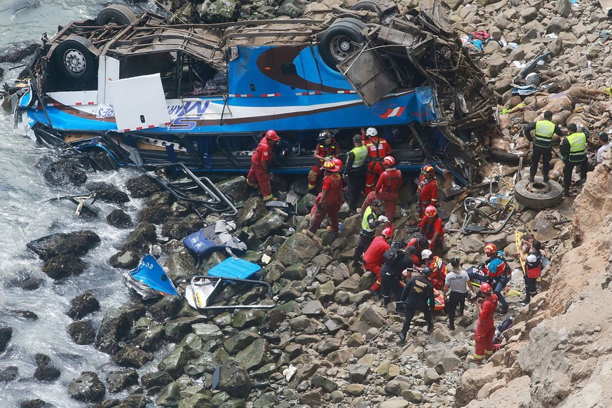 epa06413851 A handout photo made available by Agencia Andina shows a group of emergency personnel working to rescue victims after a passenger bus plunged off the Pan-American Highway North, about 45 k ...