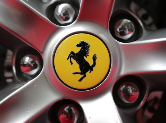 FILE - This Monday, Oct. 9, 2017 file photo shows a Ferrari logo on a car outside the New York Stock Exchange in New York. Luxury sportscar maker Ferrari says its chief executive, Louis Camilleri, has ...