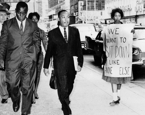 FILE-In this Oct. 19, 1960 file photo, Dr. Martin Luther King Jr. under arrest by Atlanta Police Captain R.E. Little, left rear, passes through a picket line outside Rich&#039;s Department Store, in a ...