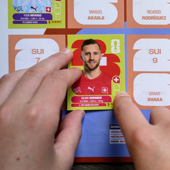 A young collector sticks a Panini World Cup sticker of the Switzerland's soccer national team player Silvan Widmer, next to Yvon Mvogo, Denis Zakaria, Fabian Rieder, Remo Freuler, Ruben Vargas, J ...