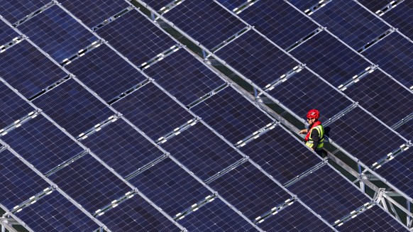 epa07906927 A worker assembles floating barges with solar panels on the Lac des Toules, an alpine reservoir lake, in Bourg-Saint-Pierre, Switzerland, 08 October 2019 (issued 09 October 2019) Upon comp ...