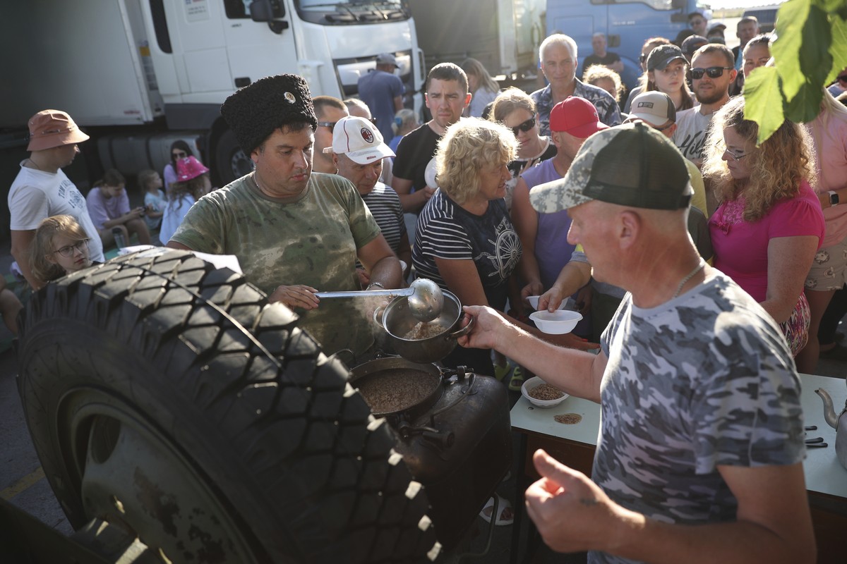 A cossack distributes buckwheat porridge to drivers and passengers who gather as they wait for a ferry to Crimea near the village of Ilyich, Krasnodar region, on Monday, July 17, 2023. An attack befor ...