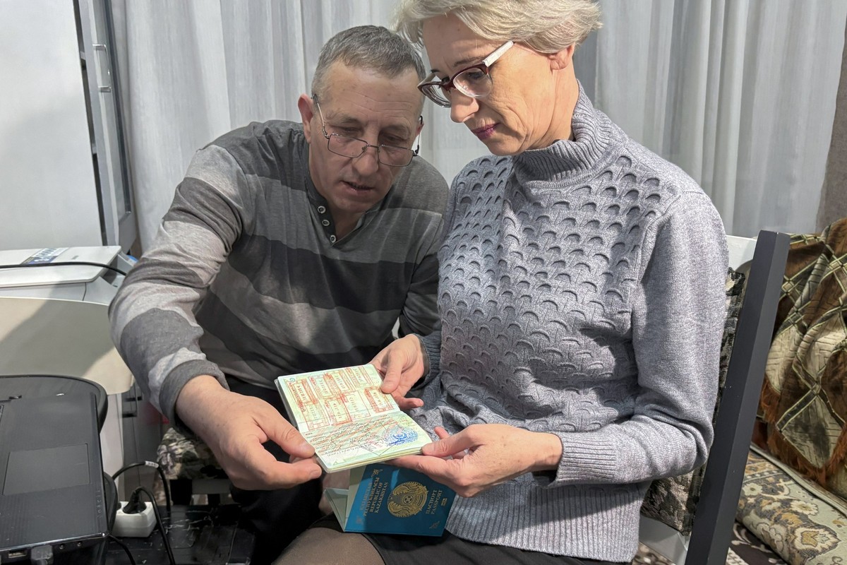 Tatiana Lopatina, the 52-year-old former sports teacher who plans to move with her husband from Kazakhstan to the city of Omsk in Russia, and her husband Dmitry look at their Kazakh passports during a ...