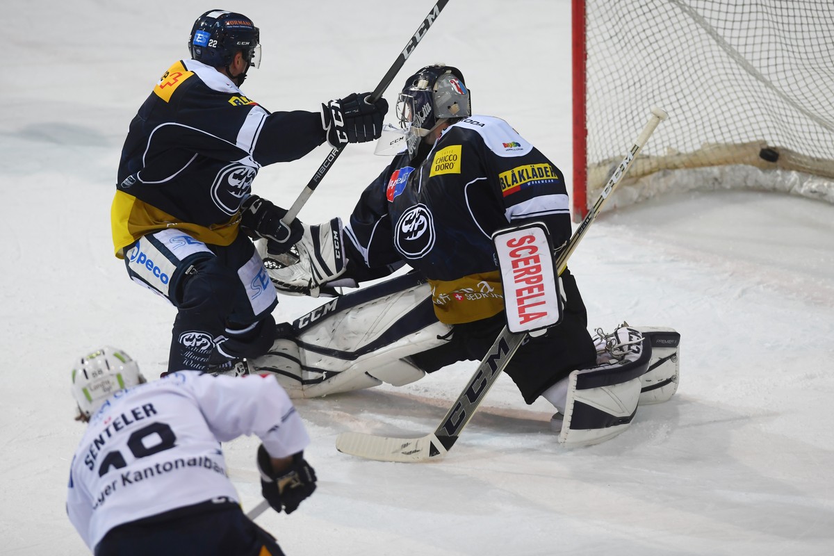 Zug's player Sven Senteler, front, scores the 2-2 goal against Ambri's goalkeeper Benjamin Conz, right, during the regular season game of the National League Swiss Championship 2018/19 betwe ...