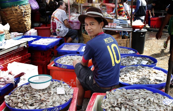 epa04266139 A Thai fresh fish-seller wearing a soccer shirt supporting Argentina&#039;s Lionel Messi sorts shrimp at Klong Toey fresh food market that is the largest of it&#039;s kind in the Thai capi ...