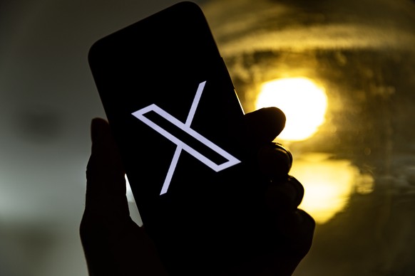 epa10772440 An illustration pictures shows a user holding a mobile phone displaying the 'X' logo, in Los Angeles, California, USA, 27 July 2023. Twitter announced on 23 July that it will reb ...
