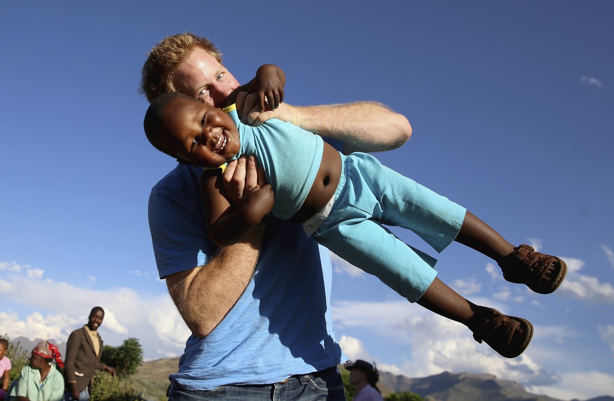 FILE - In this file photo taken on Dec. 6 2014, Britain's Prince Harry swings young three year old orphan boy Lerato in this photograph taken with the help of a three year old blind girl called K ...