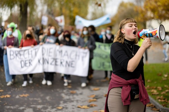 Demonstrierende laufen mit Banner und Fahnen bei einem Klimastreik gegen Grosskonzerne am Sonntag, 14. November 2021 in Zug. (KEYSTONE/Philipp Schmidli)