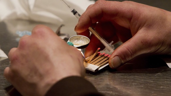 FILE - In this Wednesday, May 11, 2011, file photo, a man prepares heroin he bought on the street to be injected at the Insite safe injection clinic in Vancouver, British Columbia, Canada. The facilit ...