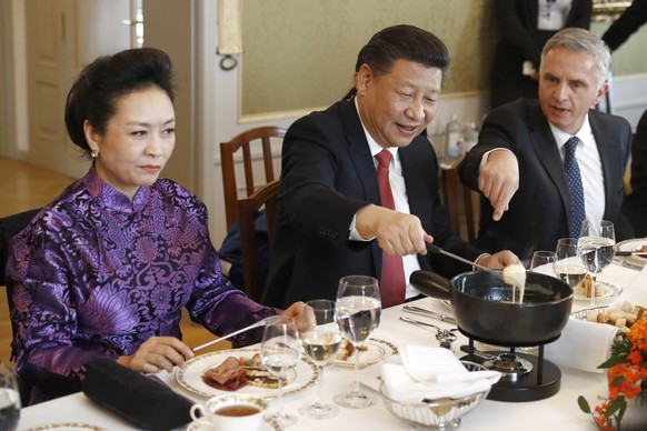 China&#039;s President Xi Jinping, center, Xi&#039;s wife Peng Liyuan, left, and Swiss Foreign Minister Didier Burkhalter eat Swiss cheese fondue during lunch during Xi&#039;s two days state visit to  ...
