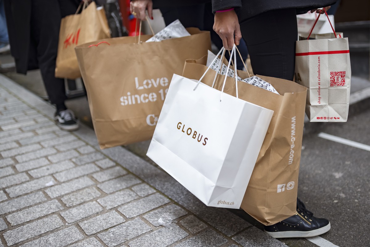Des clients attendent avec leurs achats devant un magasin a l'occasion de la journee de soldes du "Black Friday" le vendredi 27 novembre 2020 a Lausanne. (KEYSTONE/Valentin Flauraud)