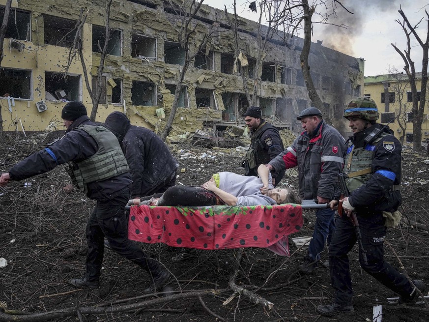 FILE - Ukrainian emergency employees and volunteers carry an injured pregnant woman from a maternity hospital that was damaged by shelling in Mariupol, Ukraine, March 9, 2022. The woman and her baby d ...