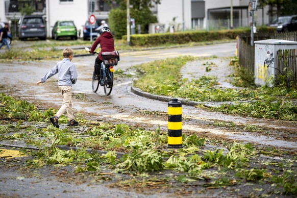 Ein Junge laeuft ueber eine mit Laub bedeckte Strasse am Freitag, 28. August 2026 in Buelach. Am Freitag sind heftige Unwetter mit Hagel ueber Teile des Kantons Aargau, Zuerich und Schaffhausen gezoge ...