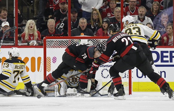 Carolina Hurricanes&#039; Micheal Ferland (79) and Nino Niederreiter (21), of Switzerland, try to score against Boston Bruins goalie Tuukka Rask (40), of Finland, while Bruins&#039; Zdeno Chara (33),  ...