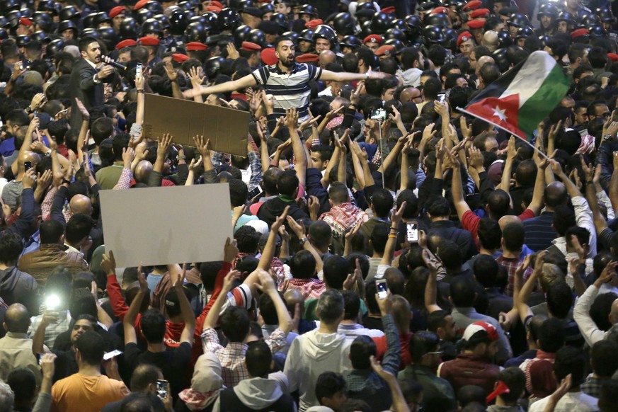 epa06783808 Jordanians protesters hold placards and shout slogans as they try to make their way to the cabinet office during a demonstration against the newly proposed income tax reforms and hike in p ...