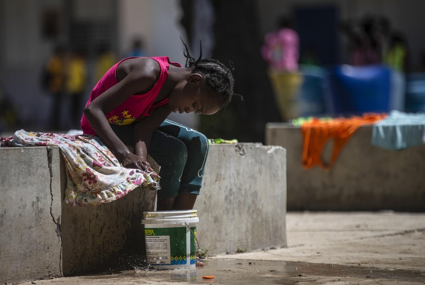 A girl washes a piece of clothing in a school turned into a shelter for families forced to leave their home in Cite Soleil due to clashes between armed gangs, in Port-au-Prince, Haiti, Saturday, July  ...