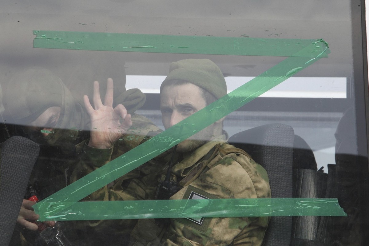A serviceman gestures as he looks from a bus window with the letter Z, which has become a symbol of the Russian military, and a hashtag reading "We don't abandon our own" in Chechnya  ...