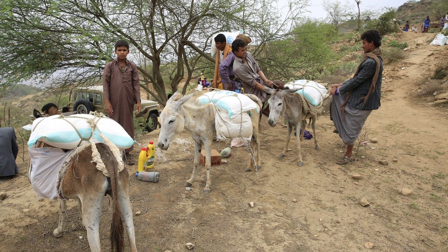 epa10074429 Yemenis upload donkeys with emergency food aid provided by Mona relief agency amid an expanded nationwide truce at a remote village in the northern province of Saada, Yemen, 14 July 2022 ( ...