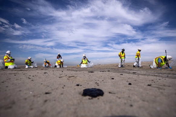 epaselect epa09506240 Crews pick the tar from the beach after an oil spill off the coast of Huntington Beach, California, USA, 04 October 2021. Roughly 126,000 gallons of oil spilled into the Catalina ...