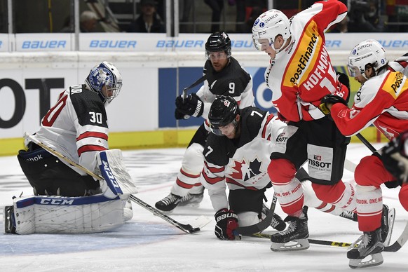 Switzerland&#039;s Gregory Hofmann, right, fights for the puck against Canada&#039;s Geoff Kinrade, center, and goalkeeper Danny Taylor, left, during the Ice Hockey Deutschland Cup at the Curt-Frenzel ...