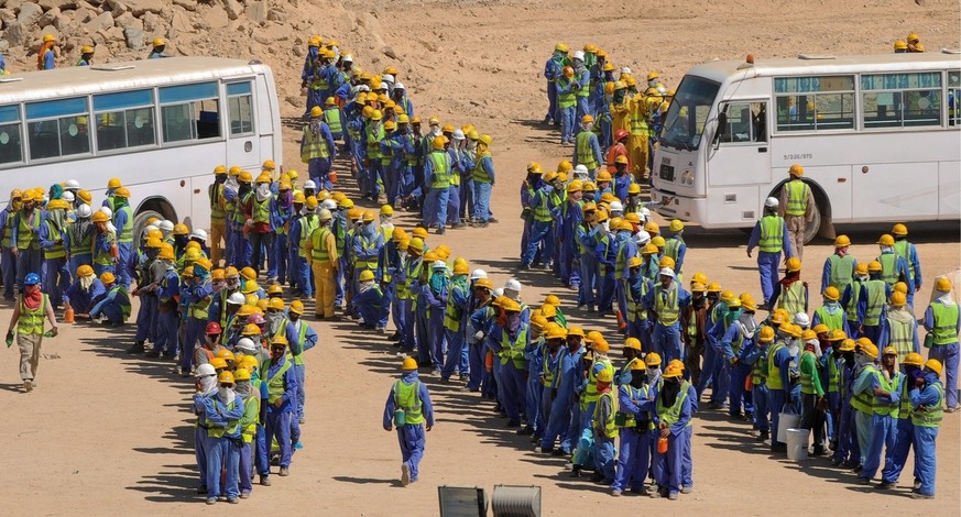 epa03956764 Foreign construction workers queue up for the bus back to their accommodation camp in Doha, Qatar, 19 November 2013. The previous day, football&#039;s ruling body FIFA said it will continu ...