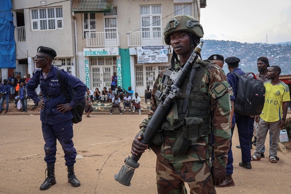 epa11916328 A soldier with the M23 armed group stands guard as a member of the Congolese National Police stands by after surrendering to the M23 armed group in Bukavu, South Kivu, Democratic Republic  ...