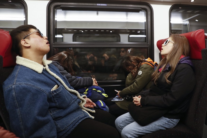 epa05936935 A photograph made available on 30 April 2017 showing Asian tourists sleeping during a train ride from Kleine Scheidegg to the Jungfraujoch, in Switzerland, 29 April 2017. EPA/PETER KLAUNZE ...