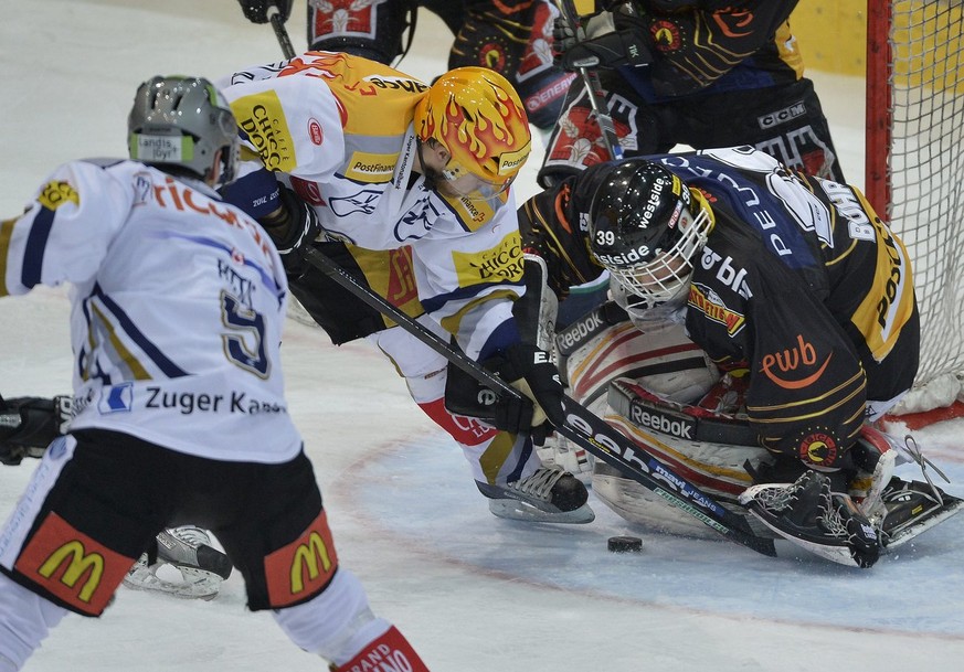 Die Zuger Domenico Pittis und Topskorer Linus Omark, von links, und der Berner Torhueter Marco Buehrer, rechts, kaempfen um den Puck im ersten Playoff-Halbfinalspiel der National League A zwischen dem ...